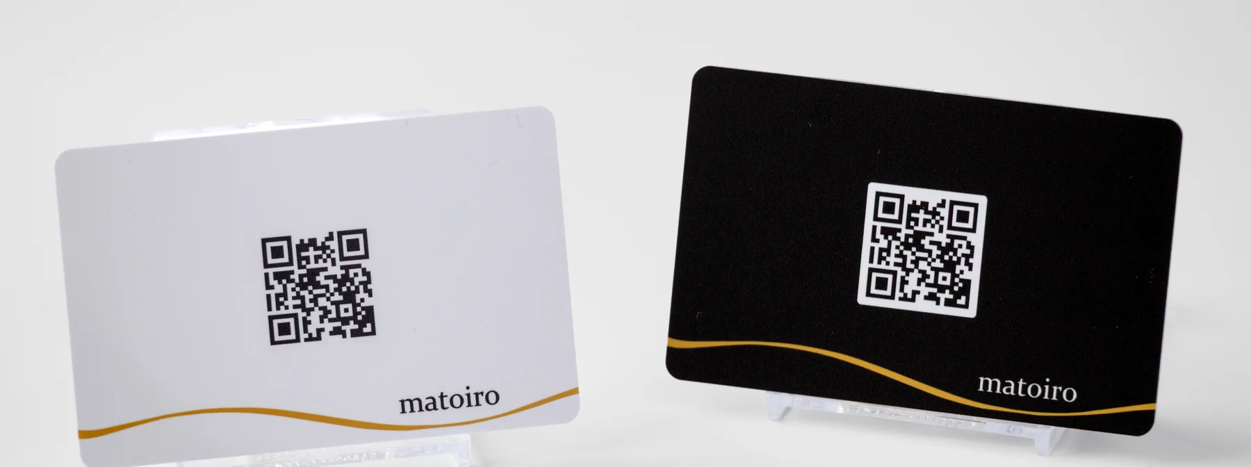 Matoiro の実物 NFC カード。生成りと墨の 2 枚、裏面に matoiro のワードマークと金の線
